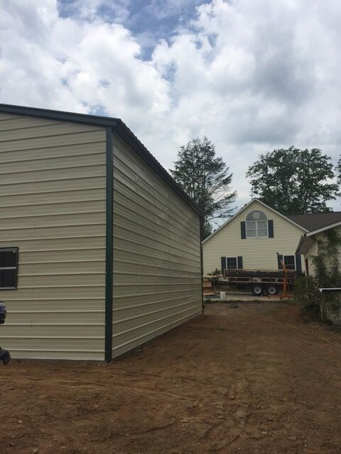 Side view of a commercial metal garage building, with beige sides and green trim.