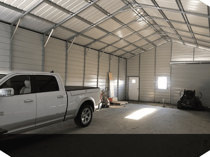 Inside of a double wide garage building with three garage doors, a window, and a single man door with a truck parked inside.
